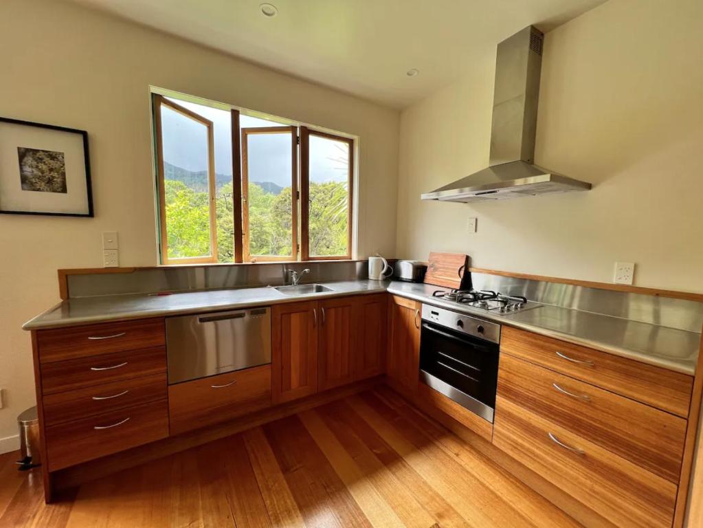 a kitchen with wooden cabinets and a stove top oven at Forest Hideaway ~ Rustic in Coromandel Town