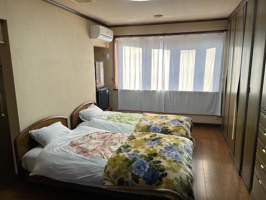 a bedroom with two beds with floral sheets and a window at 晋～SHIN～各務原 in Kakamigahara