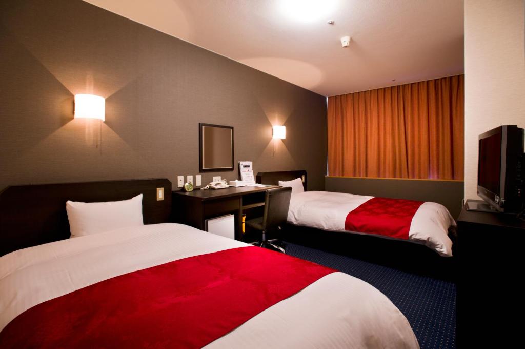 a hotel room with two beds and a television at Hotel Taisei Annex in Kagoshima