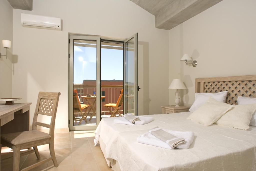 a bedroom with a bed and a desk and a balcony at Erkina Villas Kalami Corfu in Kalami