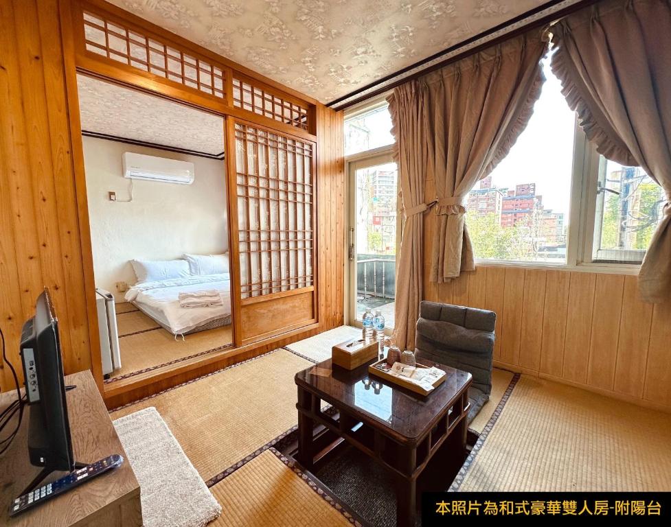 a living room with a table and a room with a bed at Ming Ren Hotspring Hotel in Jiaoxi