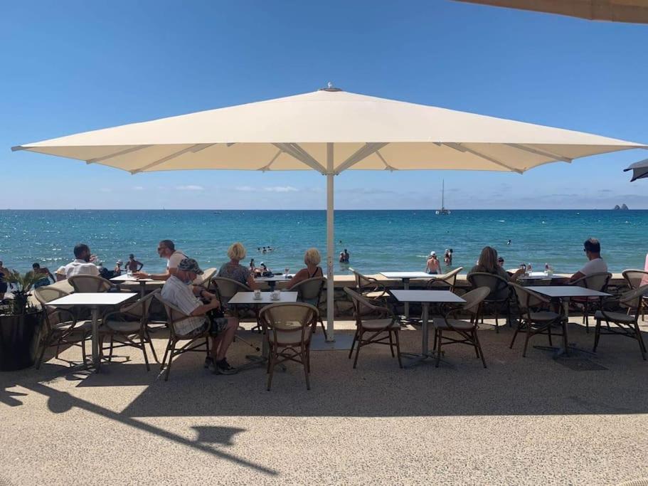 un groupe de personnes assises à des tables sous un parasol sur la plage dans l'établissement Joli T2 3mn mer. Proche commodité WiFi Parking, à La Seyne-sur-Mer