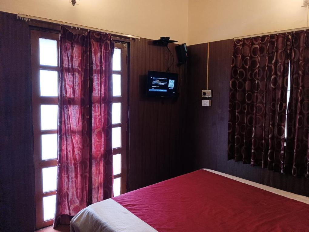 um quarto com uma cama vermelha e uma janela em FLGHR Crazy Home Stay em Kodaikanal