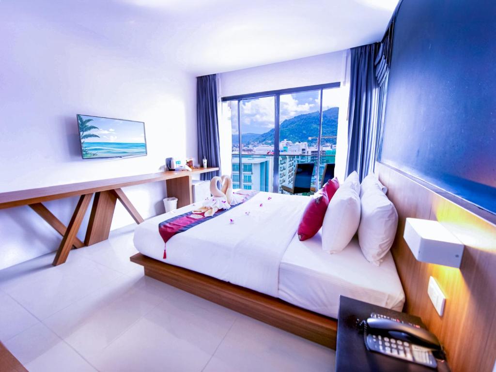 a bedroom with a large bed with a window at Phoenix Grand Patong in Patong Beach