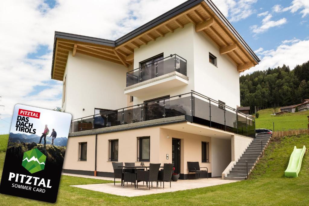 a large white house with a table and chairs at Appart Bergliebe in Arzl im Pitztal