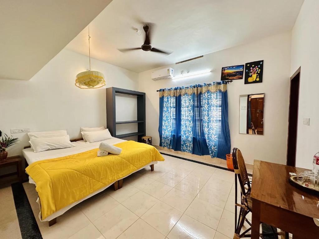 ein Schlafzimmer mit einem Bett mit einer gelben Decke in der Unterkunft Varkala Villa in Varkala