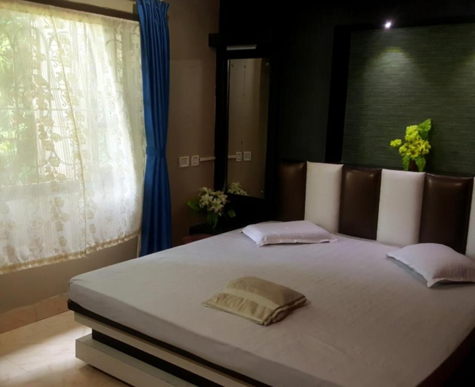 a bedroom with a large white bed with a window at Hotel Mountain View in Kalimpong
