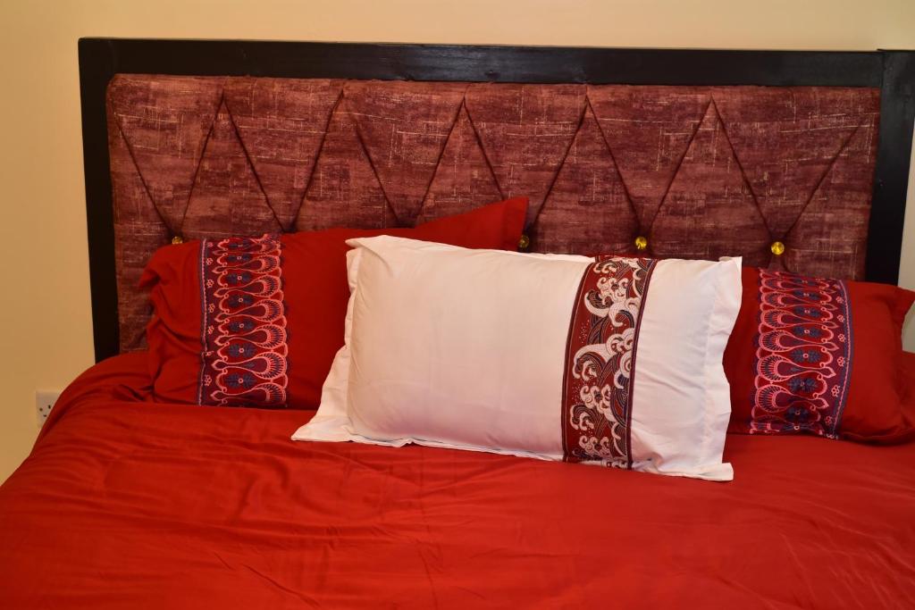 un letto rosso con cuscini rossi e bianchi di Dennis Prince pm comfy home a Nairobi