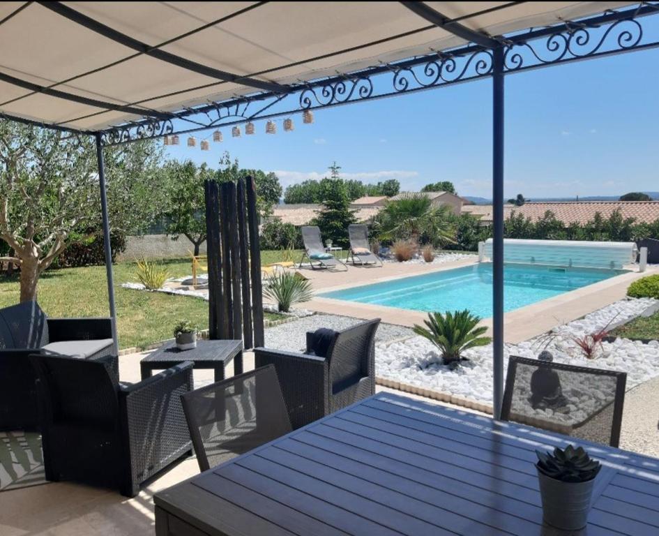 un patio avec une table et des chaises et une piscine dans l'établissement Charmante Villa avec Piscine, à Saint-Marcel-dʼArdèche