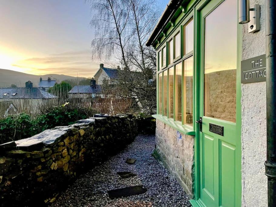a green door on a building with a stone wall at Stunningly stylish cottage. in Bradwell