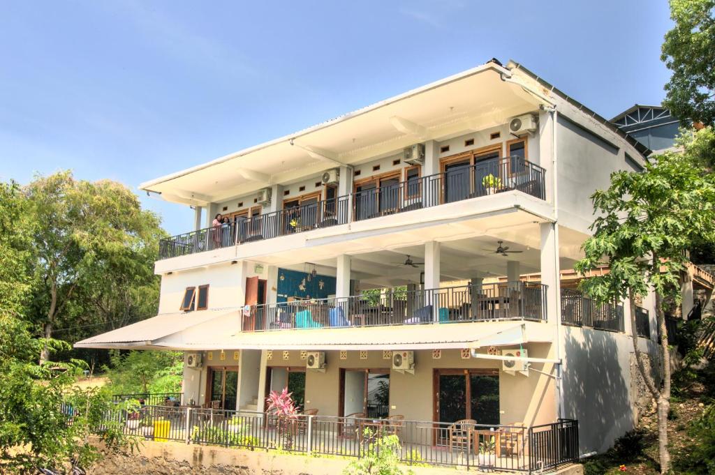 un gran edificio blanco con balcones y árboles en Hotel Bonne Nuit, en Labuan Bajo