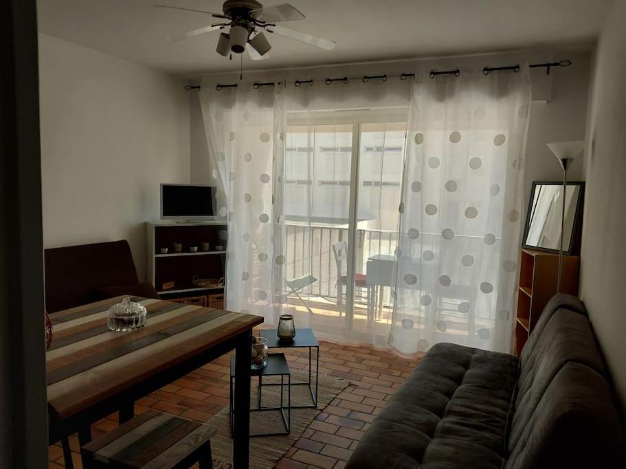 un salon avec un canapé et une porte coulissante en verre dans l'établissement Au calme à 2min mer Parking Balcon Wifi Clim!, à Six-Fours-les-Plages