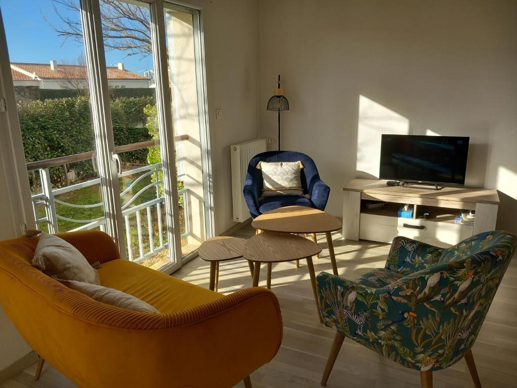 Una sala de estar con un sofá y sillas y un televisor. en Appartement 2 chambres proche Grande Plage, en Saint Gilles Croix de vie