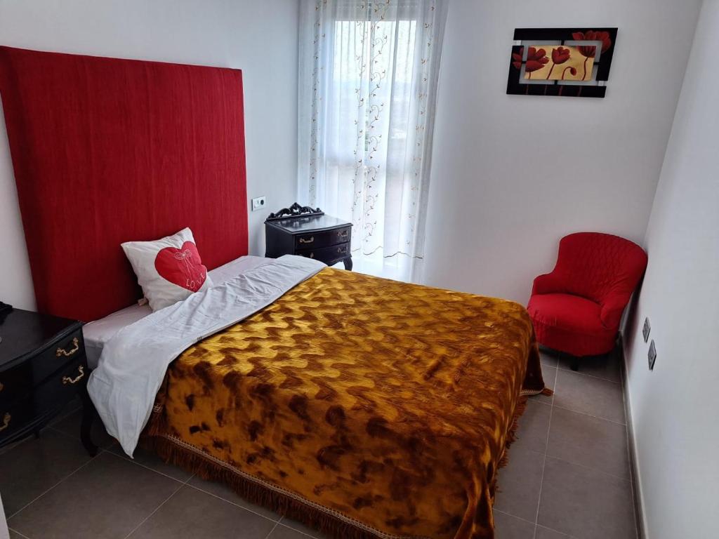 Castellon, Moncofar playa في مونوكوفار: غرفة نوم بسرير وكرسي احمر