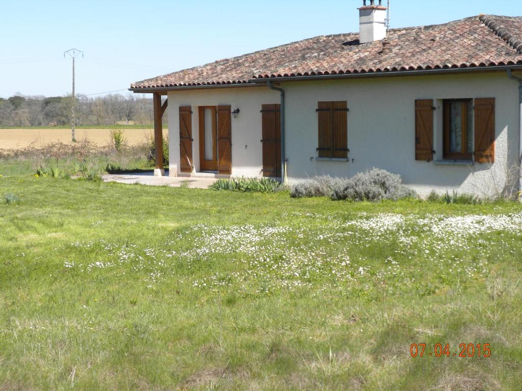 una pequeña casa blanca en un campo de hierba en Maison de Vacances de Récailleau en Nérac