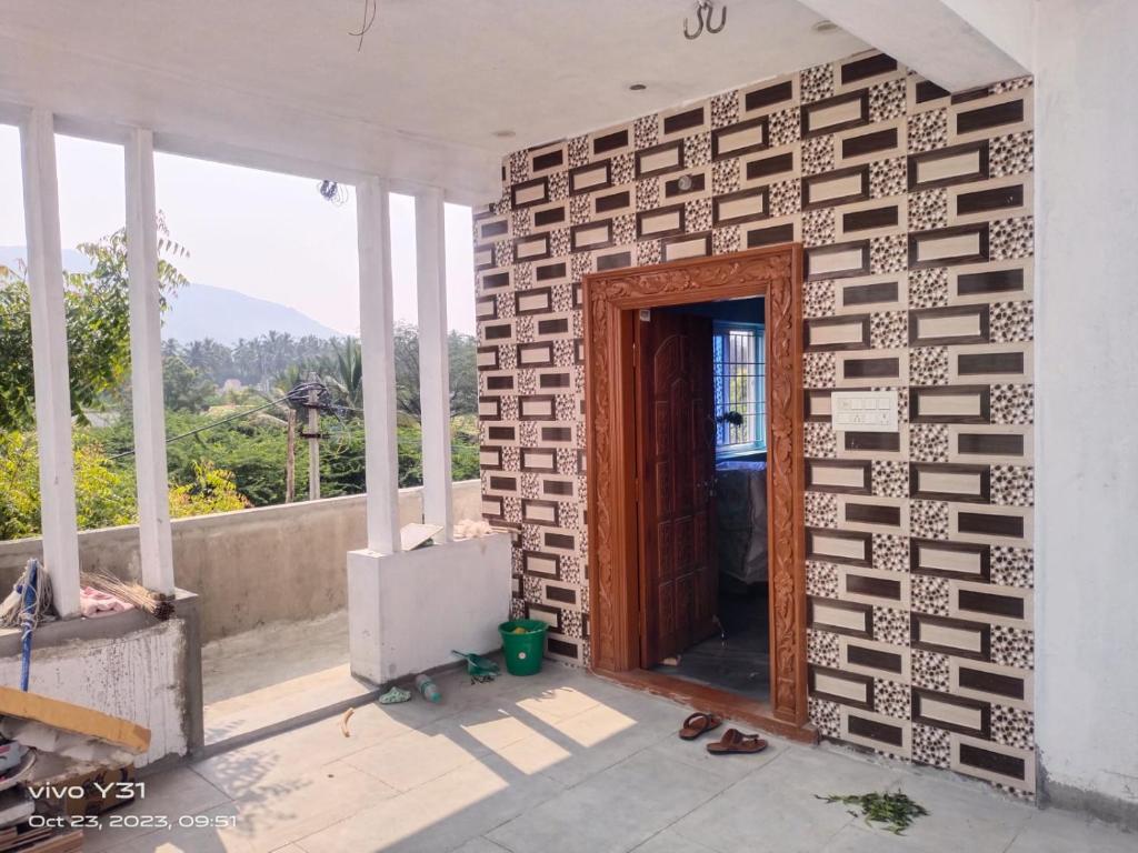 um quarto com uma parede de tijolos e uma porta de madeira em BHARATH VILLAS em Vāniyambādi
