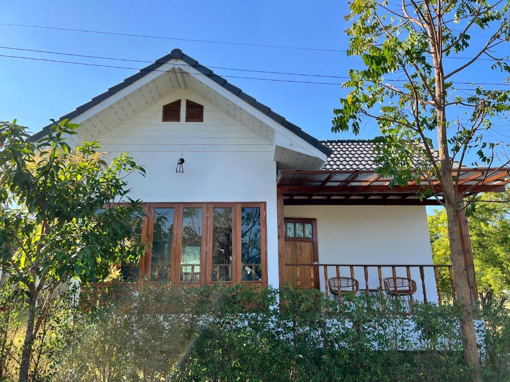 une maison blanche avec une terrasse couverte et des chaises dans l'établissement บ้านโรสแมรี่ By ชมภู ชุมแพ โฮมสเตย์ ไร่คุณต๋ง, 
