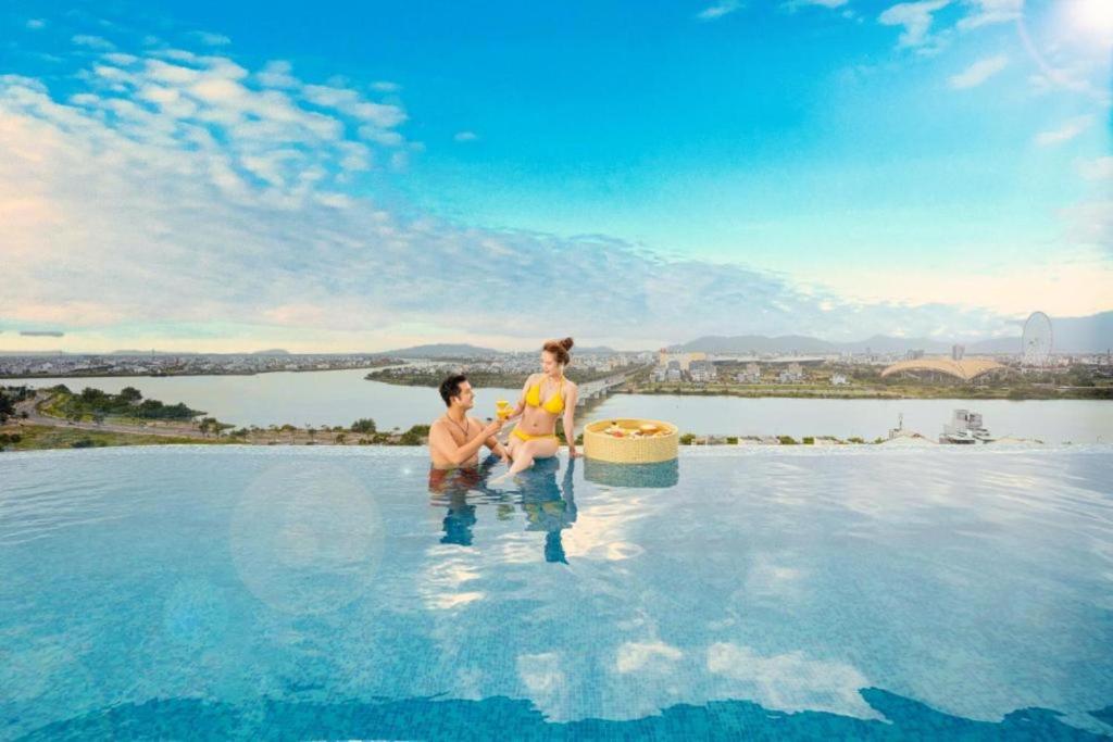 duas pessoas sentadas na piscina de beiral infinito de um resort em RHM Luxury Hotel And Suite em Da Nang