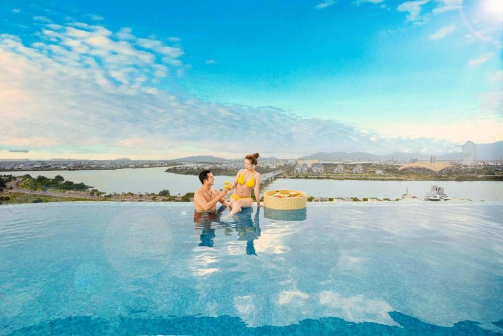 two people sitting in the infinity pool at a resort at RHM Luxury Hotel And Suite in Danang