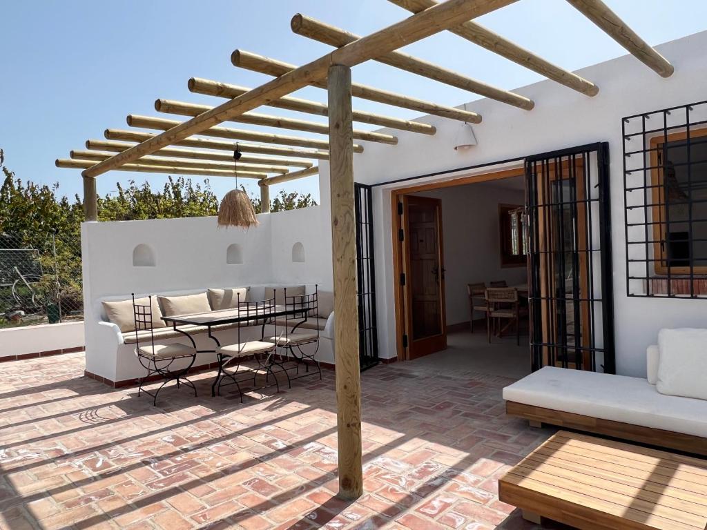 un patio con pérgola de madera, mesa y sillas en Cortijo Cantalobos, en Almuñécar