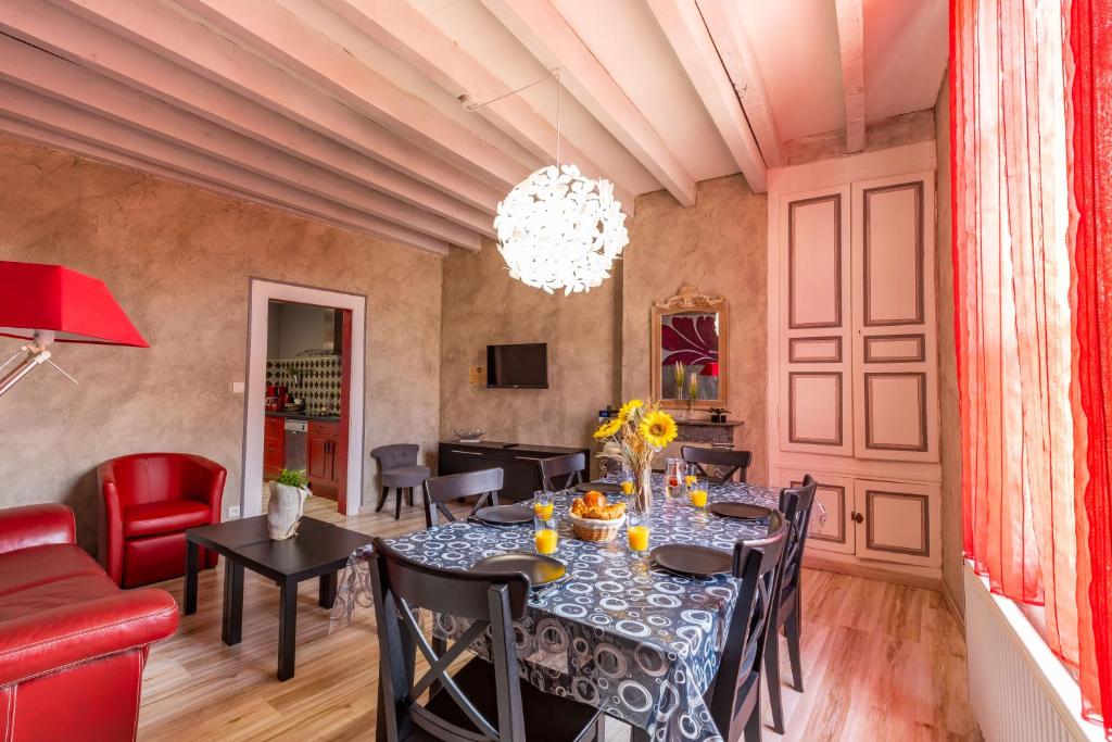 a dining room with a table and chairs and a chandelier at La Belle Grace in Saint-Aignan