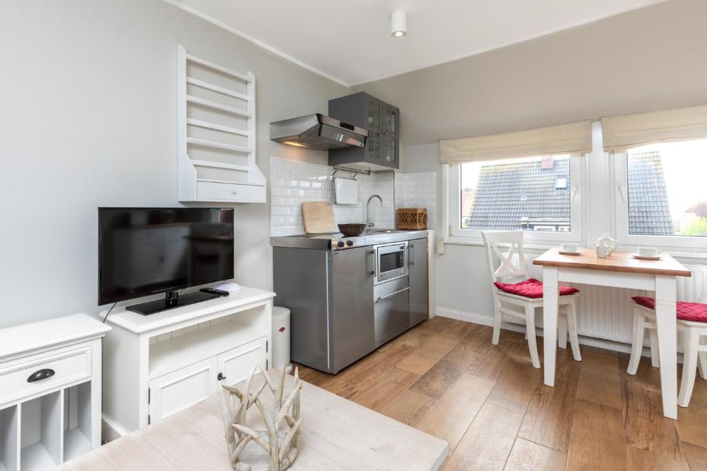 a kitchen with white cabinets and a table with a dining room at Haus Delft Baoule in Juist