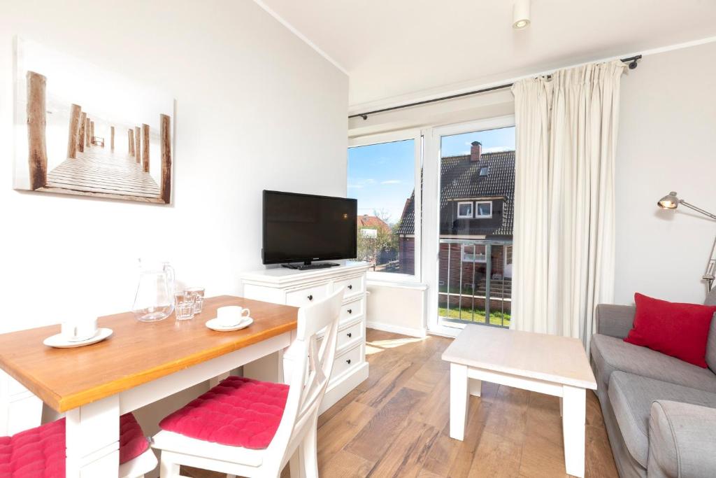 a living room with a table and a tv and a couch at Haus Delft Elisa in Juist