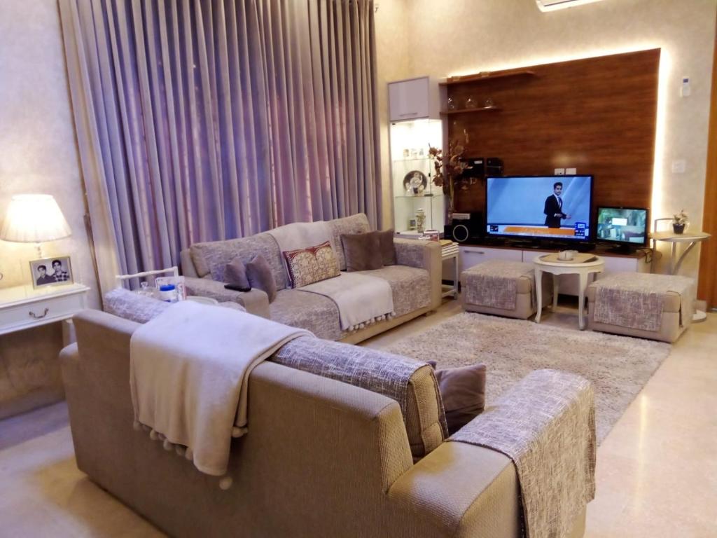 Il comprend un salon avec des canapés et une télévision à écran plat. dans l'établissement Independent House in Islamabad with Lawn Airport 15 min, à Islamabad