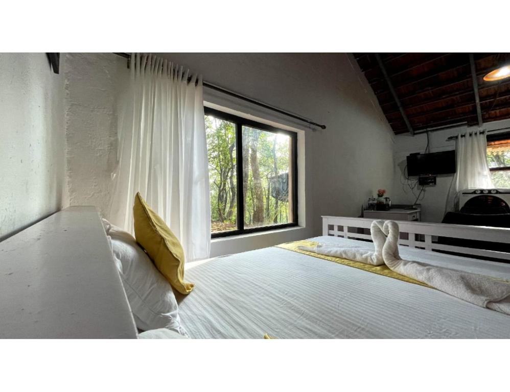 - une chambre avec un grand lit et une fenêtre dans l'établissement The Earthen Nest Resort, Canacona, Goa, à Poinguinim