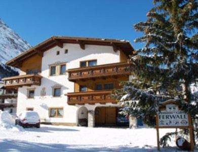 a large building in the snow next to a tree at Garni Ferwall in Galtür