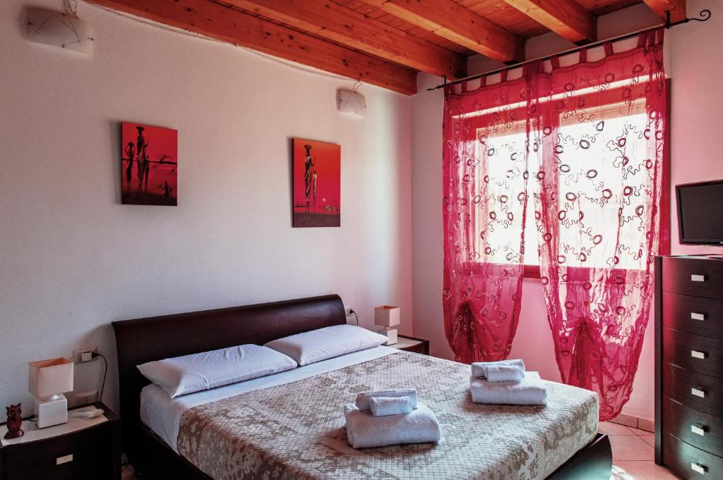 a bedroom with a bed and a window with red curtains at Casa Azzurra in San Sperate