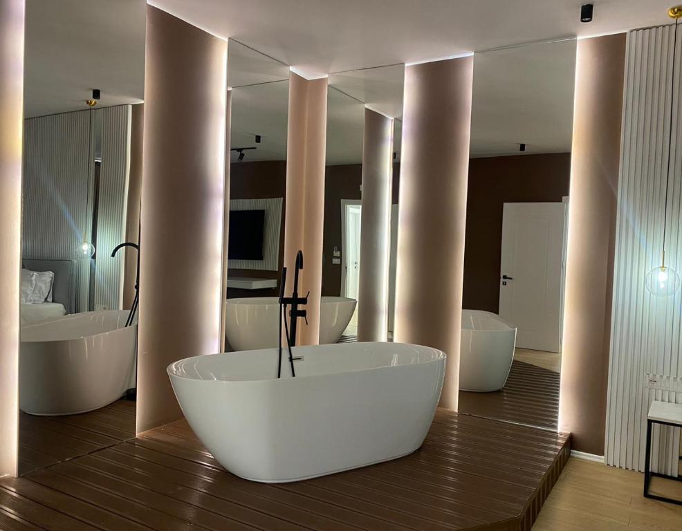 La salle de bains est pourvue d'une baignoire, de deux lavabos et de miroirs. dans l'établissement Capital Suites Center, à Tirana