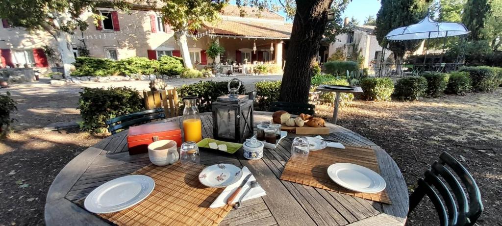 a wooden table with plates of food on it at Chambre d&#39;Hotes Lamanon, avec ou sans petit déjeuner - Domaine Les Peupliers - in Lagnes