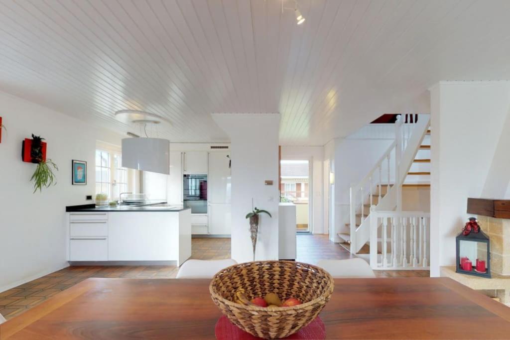 uma cozinha e sala de estar com uma cesta de frutas sobre uma mesa em Cheerful villa with fireplace, bath-tub and garden em Noville