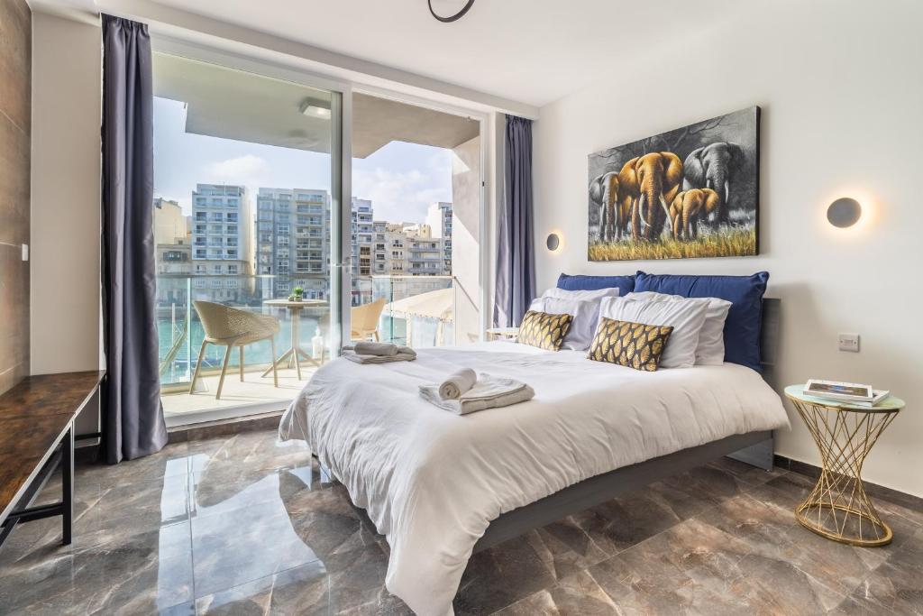 ein Schlafzimmer mit einem großen Bett und einem großen Fenster in der Unterkunft Spinola Studio Deluxe, StJulians in St Julian's