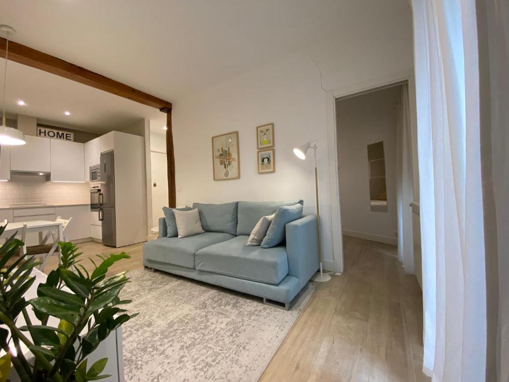 a living room with a blue couch and a kitchen at Apartamento Urdaneta in San Sebastián