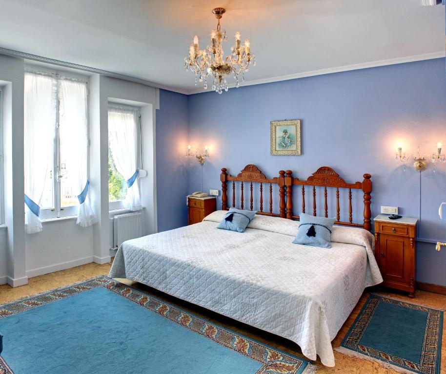 a bedroom with a bed with blue walls and a chandelier at Villa La Argentina in Luarca