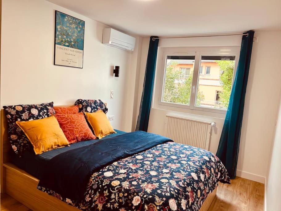 a bedroom with a bed with colorful pillows and a window at An Exceptional Apartment, 20 Min Paris, 10 Min Orly Airport, 30 Min Disney, 25 Min Versailles, Parking free in Antony