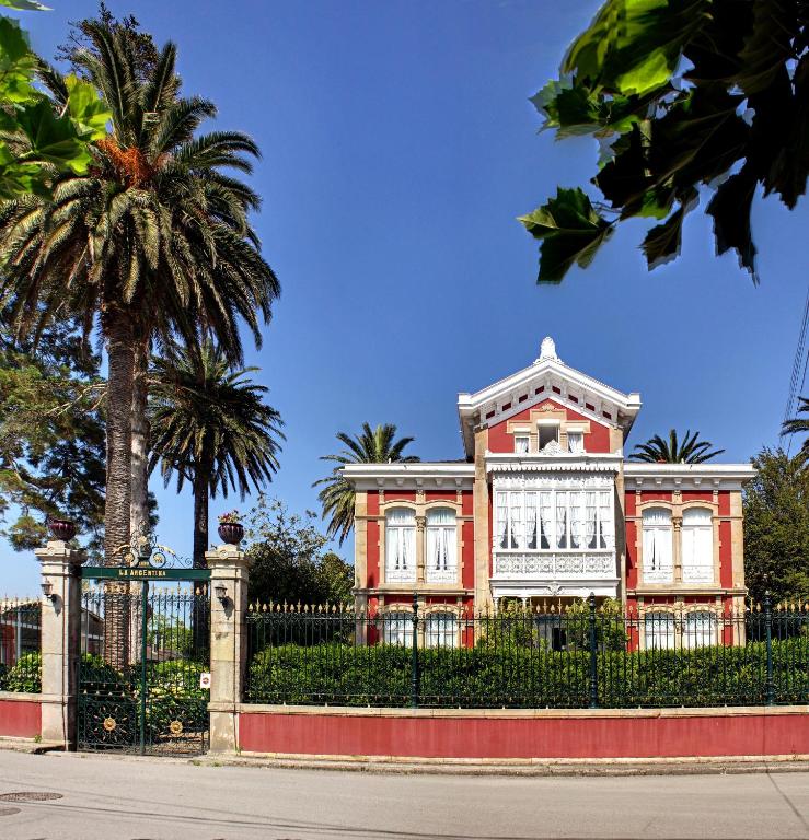 a house with a palm tree in front of a fence at Villa La Argentina in Luarca
