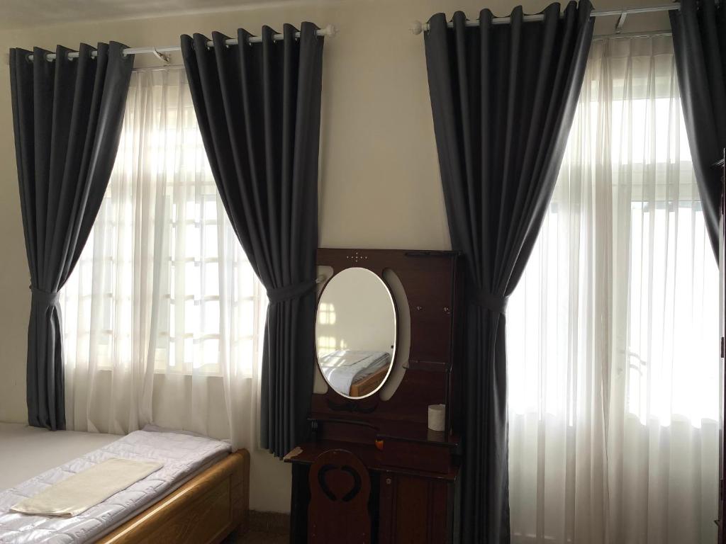 una camera da letto con tende nere e specchio di Khách sạn Ngọc Hồi 2 a Buôn Kô Sir
