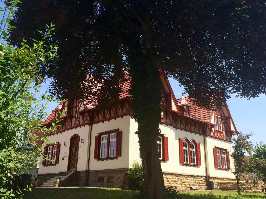 a large house with red windows and a tree at Gästehaus "Unsere Stadtvilla" in Hechingen