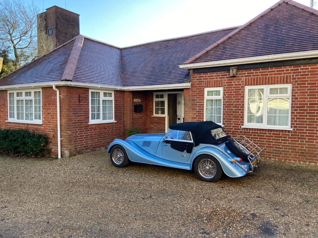 a blue car parked in front of a brick house at The Bothy in Lyndhurst