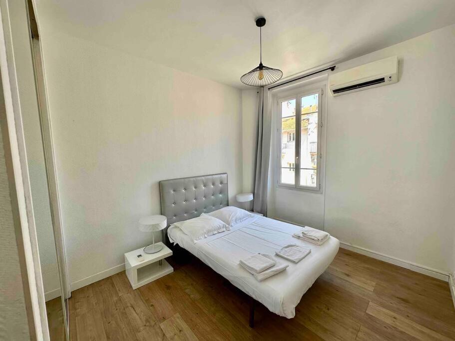 Habitación blanca con cama y ventana en Agréable deux pièces spacieux / climatisé / balcon, en Niza