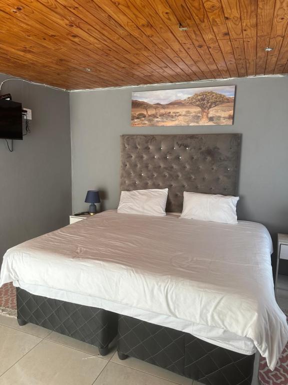 een groot bed in een slaapkamer met een houten plafond bij KKK Guesthouse in Secunda