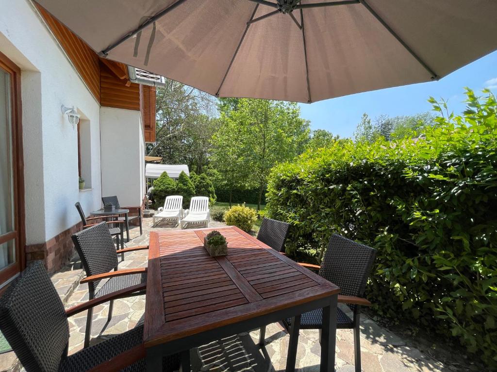 Appartement Kastelo Teraso في زالاكساني: طاولة وكراسي خشبية مع مظلة على الفناء