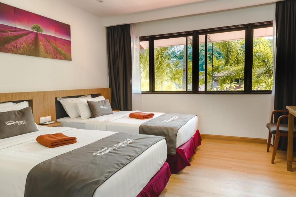 two beds in a hotel room with windows at Pangkor Sandy Beach Resort in Pangkor