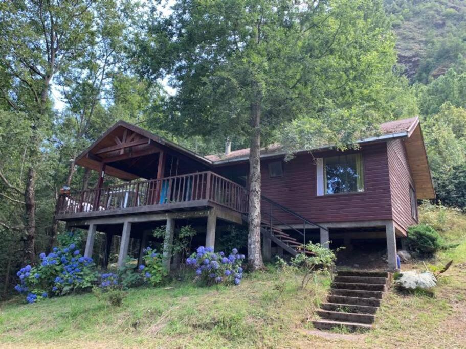 een huis op een heuvel met bloemen ervoor bij Casa Orilla Lago Cólico in Cunco