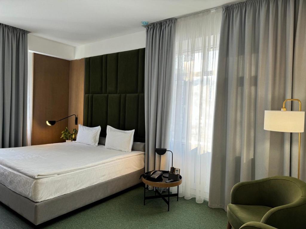 um quarto com uma cama, uma cadeira e uma janela em Evropa Hotel em Bishkek