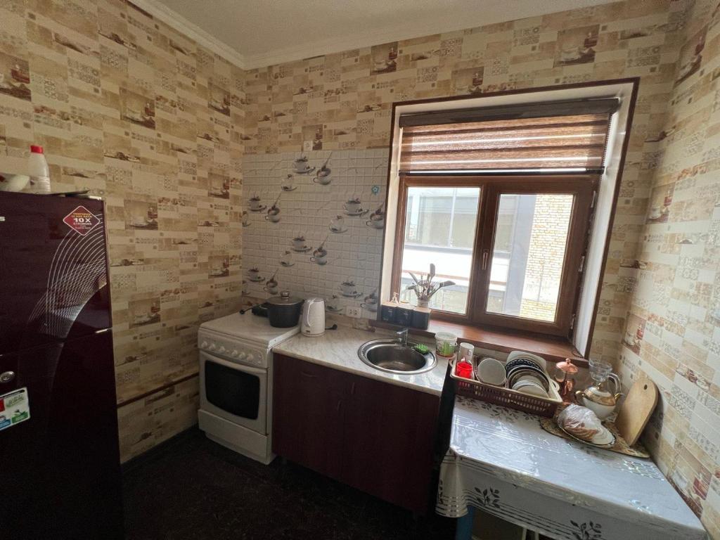 una pequeña cocina con fregadero y ventana en Khamza Hostel en Bukhara