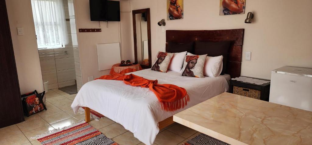 Un dormitorio con una cama con una bufanda naranja. en BluePalms Guesthouse, en Swakopmund